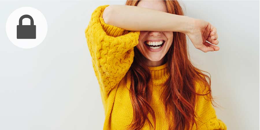 Attractive young woman laughing and hiding her face behind her arm.