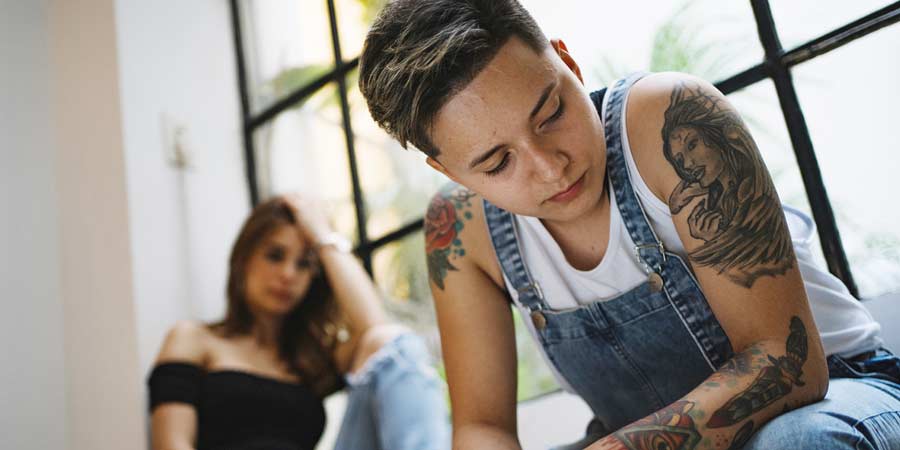 Lesbian woman looking upset after breaking up with her queer girlfriend